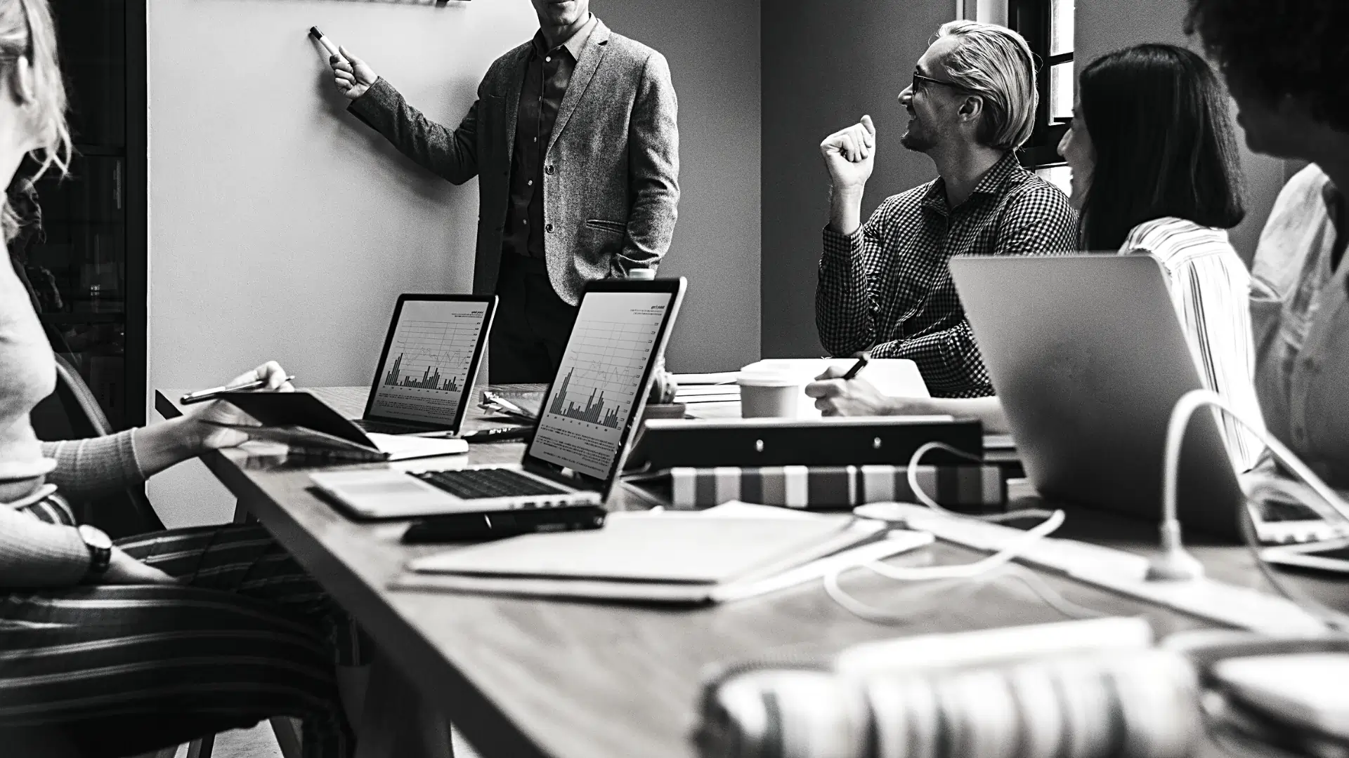 Mesa ao centro com pessoas ao redor em uma reunião, representando a forma como os impostos sobre empresas impactam as corporações.
