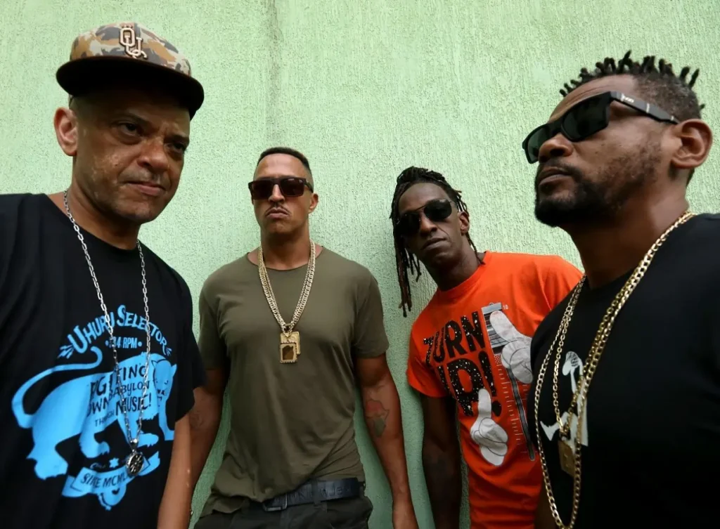 A imagem é uma foto de KL Jay, Mano Brown, Ice Blue e Edi Rock. eles aparecem lado a lado.