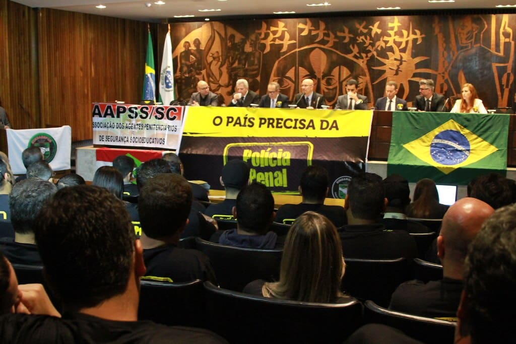 Na imagem, uma faixa com a frase "o país precisa da polícia penal".