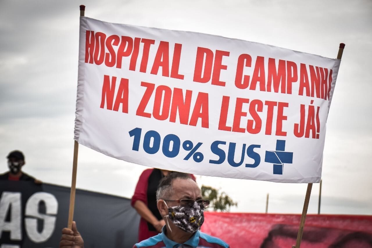 Homem segura cartaz com a frase "Hospital de Campanha na Zona Leste Já. 100% SUS"