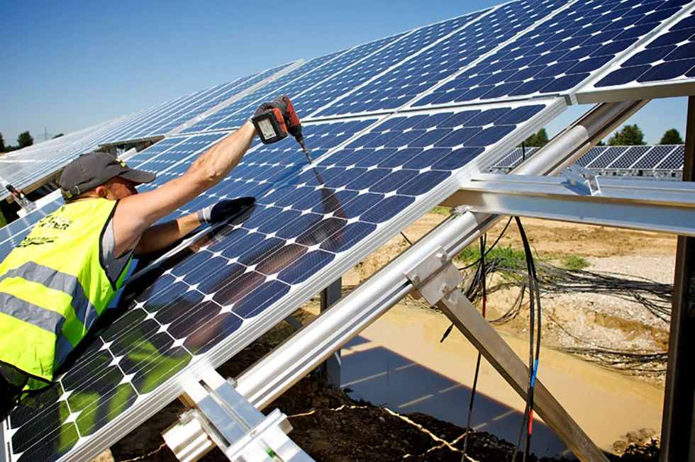  Foto de um homem instalando um painel solar para representar a ampliação da energia renovável no país 