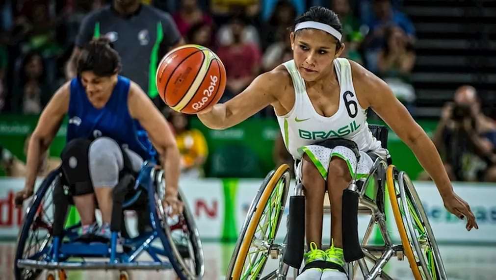 atleta do Brasil em cadeira de rodas com a bola de basquete na mão durante jogos olímpicos.