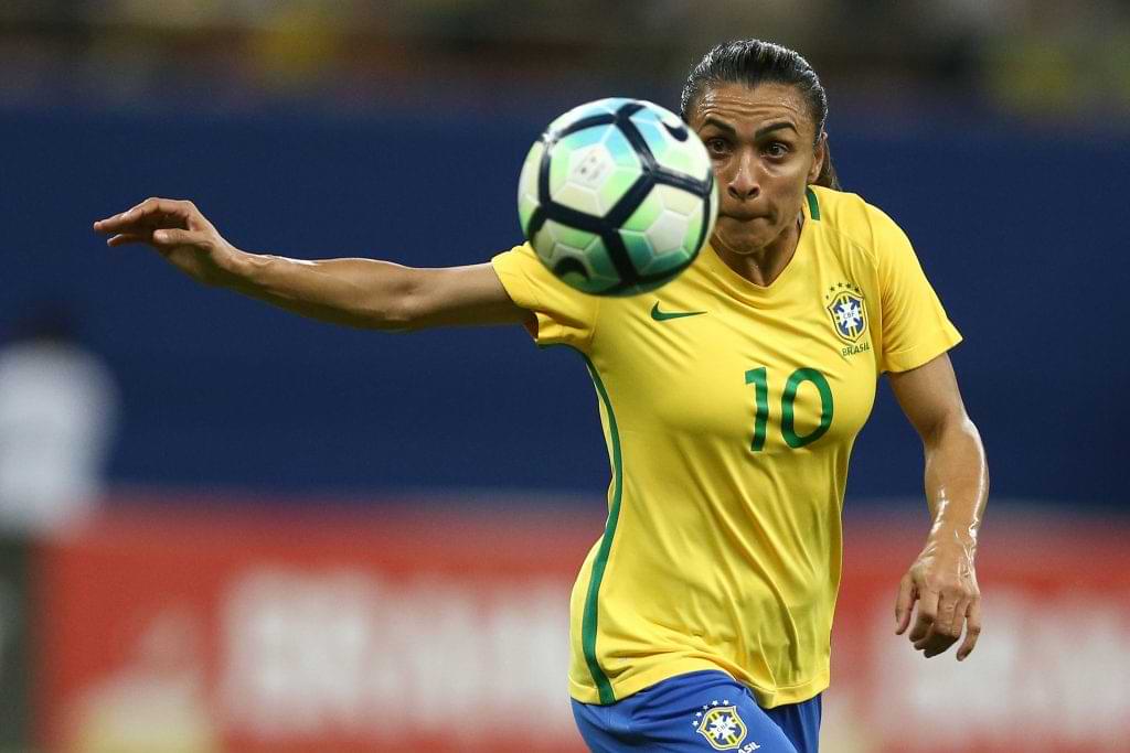 Marta jogando futebol encarando a bola no ar.