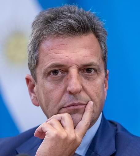 Homem branco com cabelos grisalhos curtos penteados para lado, na foto possui um olhar sério e está usando um terno azul.